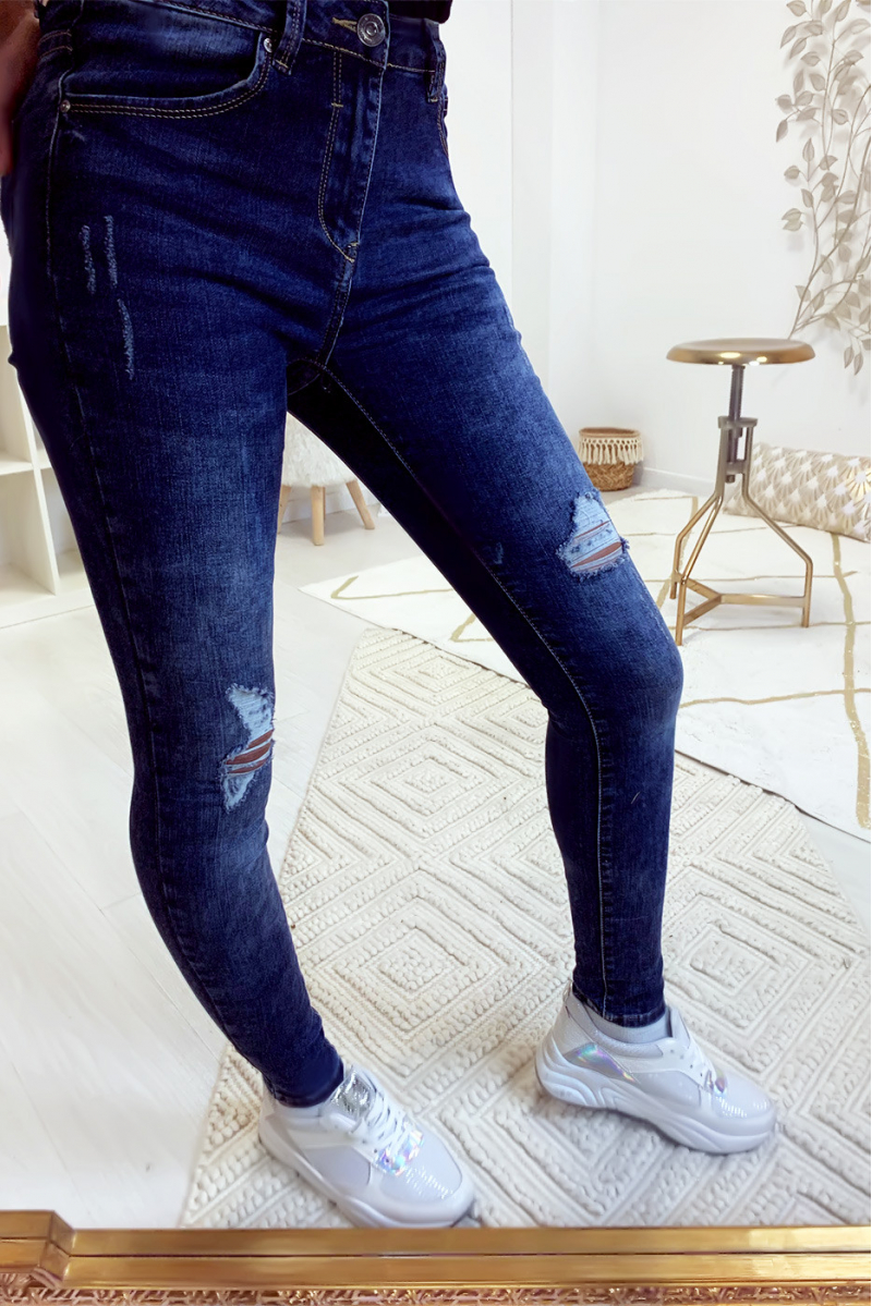 Donkerblauwe smalle jeans vervaagde en gescheurd bij de knieën